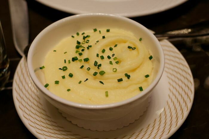 Puré de papa con cebollino en plato blanco servido en avión