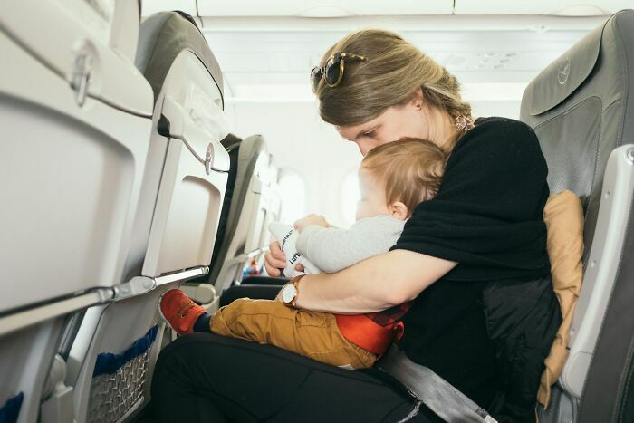 Madre con niño jugando en asiento de avión durante vuelo