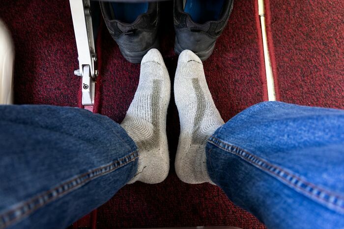 Pies con calcetines en espacio reducido y zapatos al frente en avión