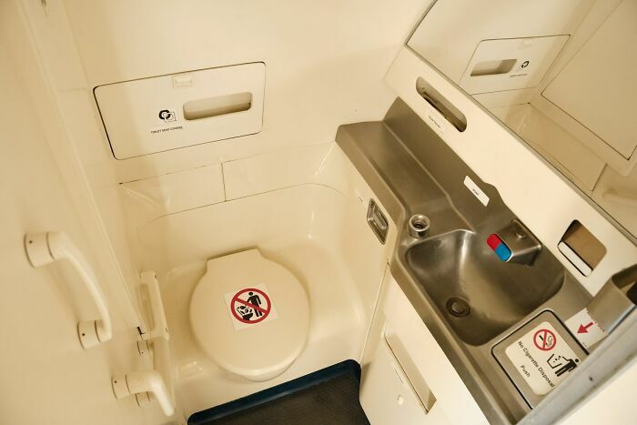 Interior del baño pequeño de avión mostrando lavabo y inodoro