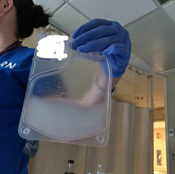 Persona con guantes sosteniendo bolsa médica transparente en hospital