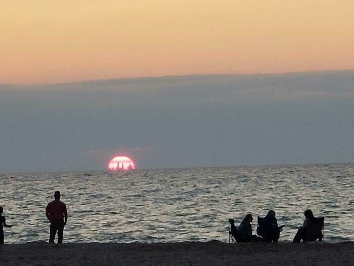 Personas disfrutando atardecer en la playa con publicación de preguntas ¿Qué pasaría si?