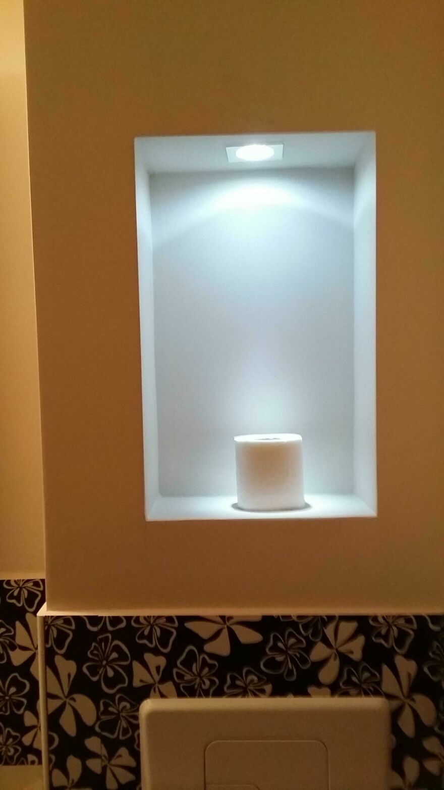 Rollo de papel higiénico iluminado en nicho de baño