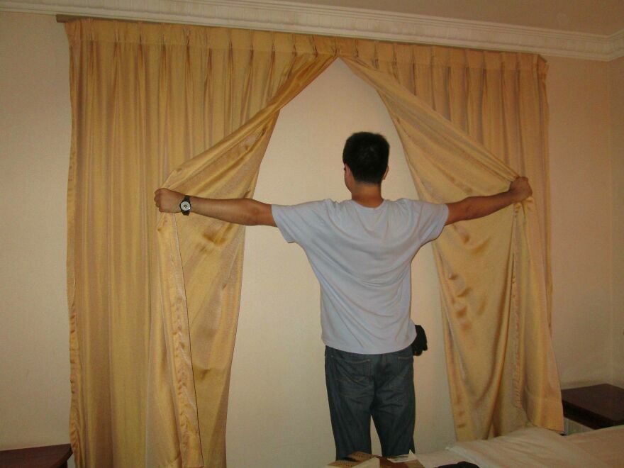 Huésped abre cortinas que cubren una pared en habitación