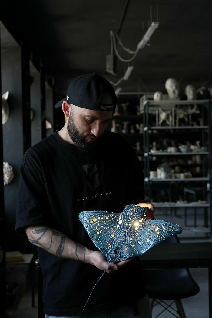 Artista mostrando una lámpara artesanal con diseño detallado en un taller de creaciones geniales