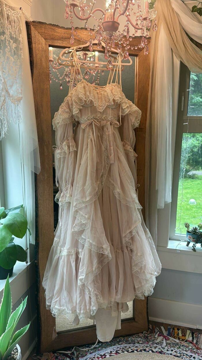 Vestido de encaje vintage colgado frente a espejo, una creación genial