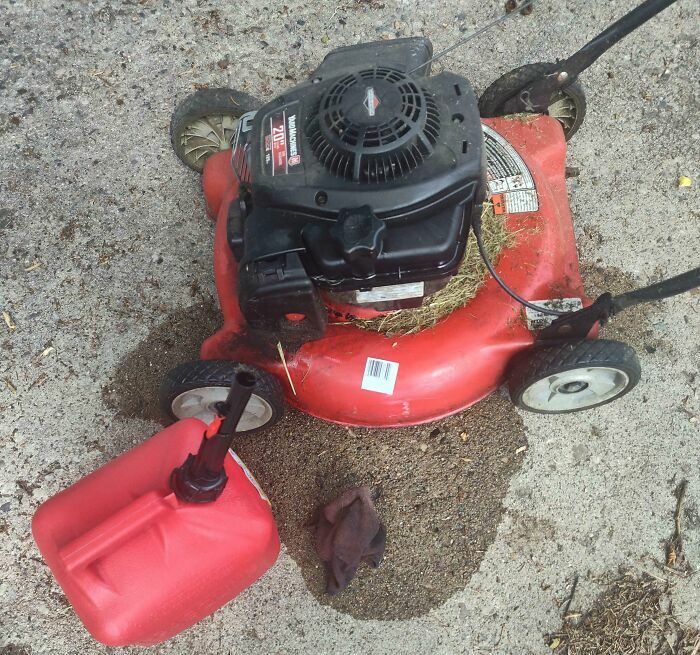 Cortadora de césped con derrame de gasolina en el suelo, fallo en mantenimiento
