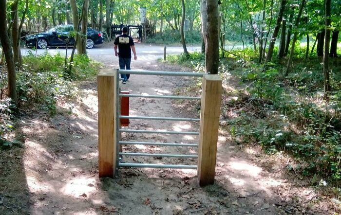 Barrera con diseño fallido que bloquea paso en camino de bosque.