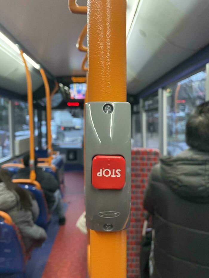 Botón de parada invertido en barra de sujeción dentro de un autobús