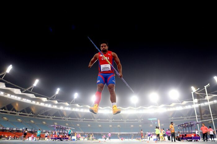 Atleta cubano compitiendo en jabalina en estadio iluminado por los Premios de fotografía Siena