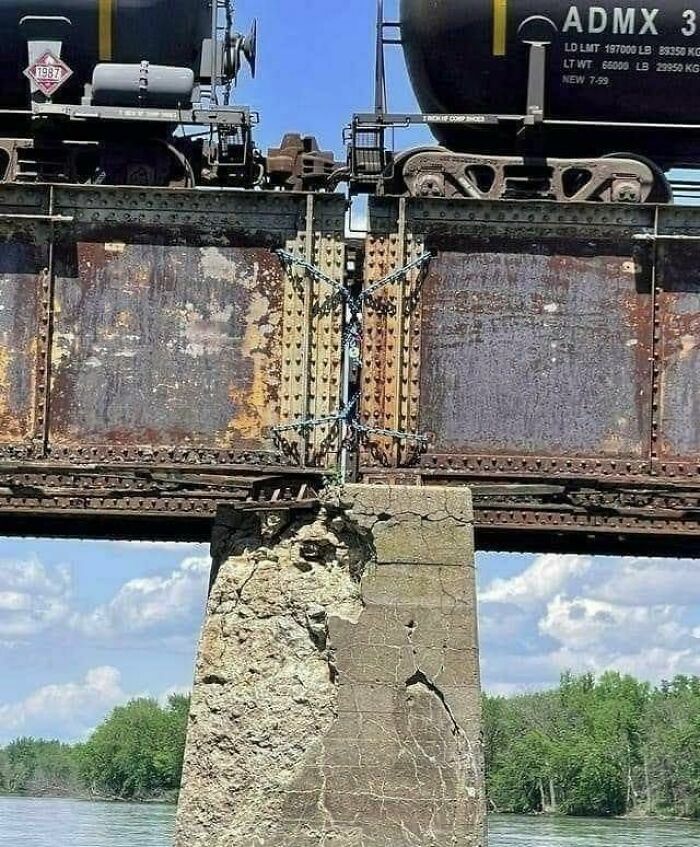 Puente de tren deteriorado atado con cadenas, evidenciando graves fallos de construcción.