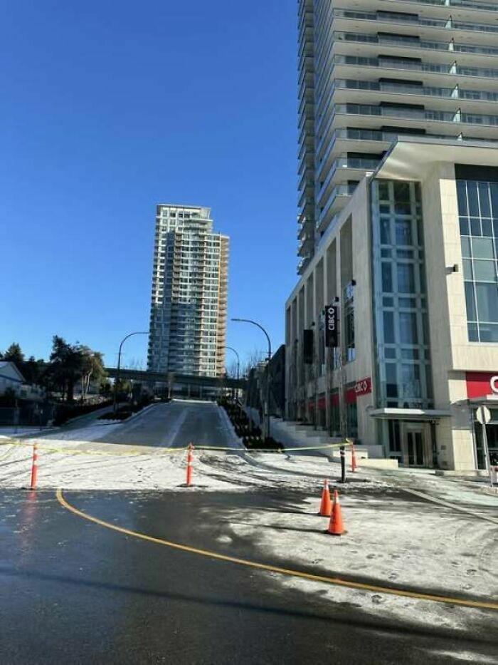 Fallos de construcción en una calle vacía acordonada cerca de edificios modernos.