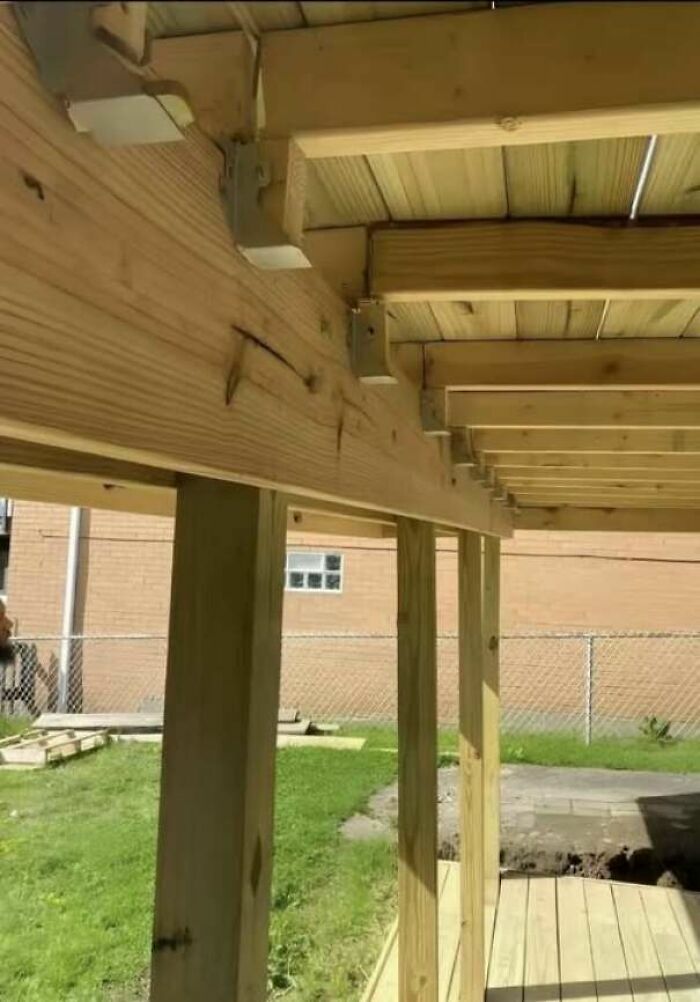 Estructura de terraza de madera con fallos de construcción en los soportes metálicos.