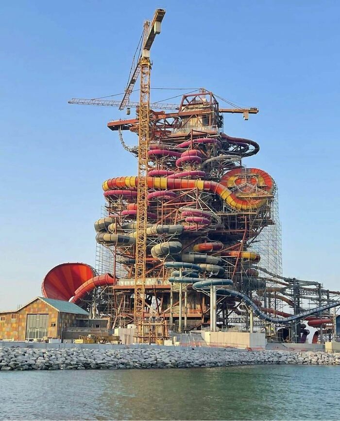 Estructura masiva de toboganes de agua en construcción con una grúa, mostrando fallos de construcción visuales.