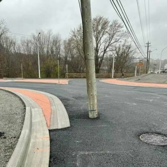 Un poste de luz atravesando el asfalto en medio de una calle, claro ejemplo de fallos de construcción.