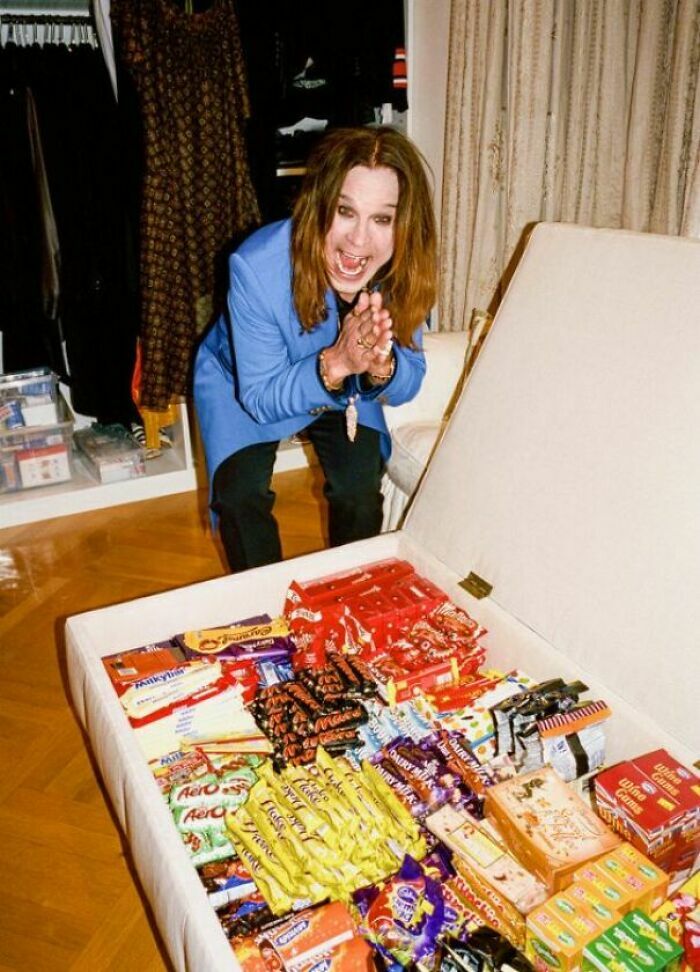 Ozzy Osbourne sonriendo emocionado junto a un baúl lleno de dulces, imágenes reconfortantes.