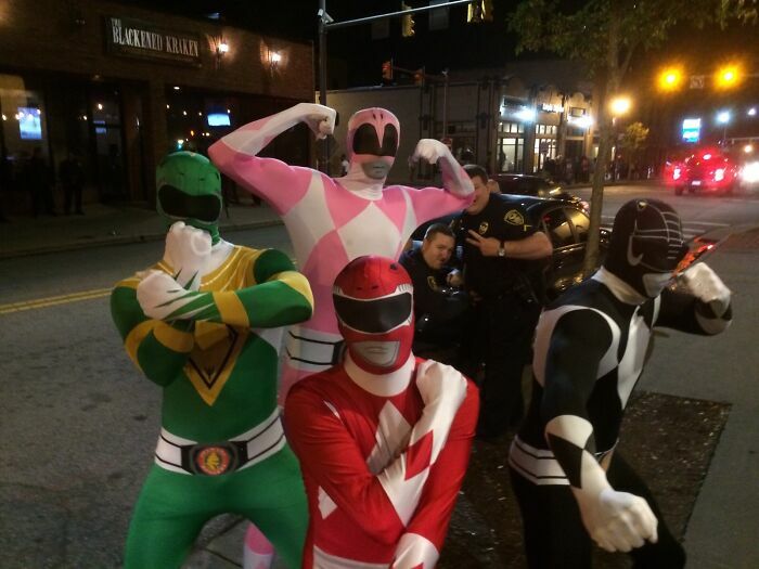 Personas disfrazadas de Power Rangers posando mientras policias sonrien al fondo en divertidas fotos.
