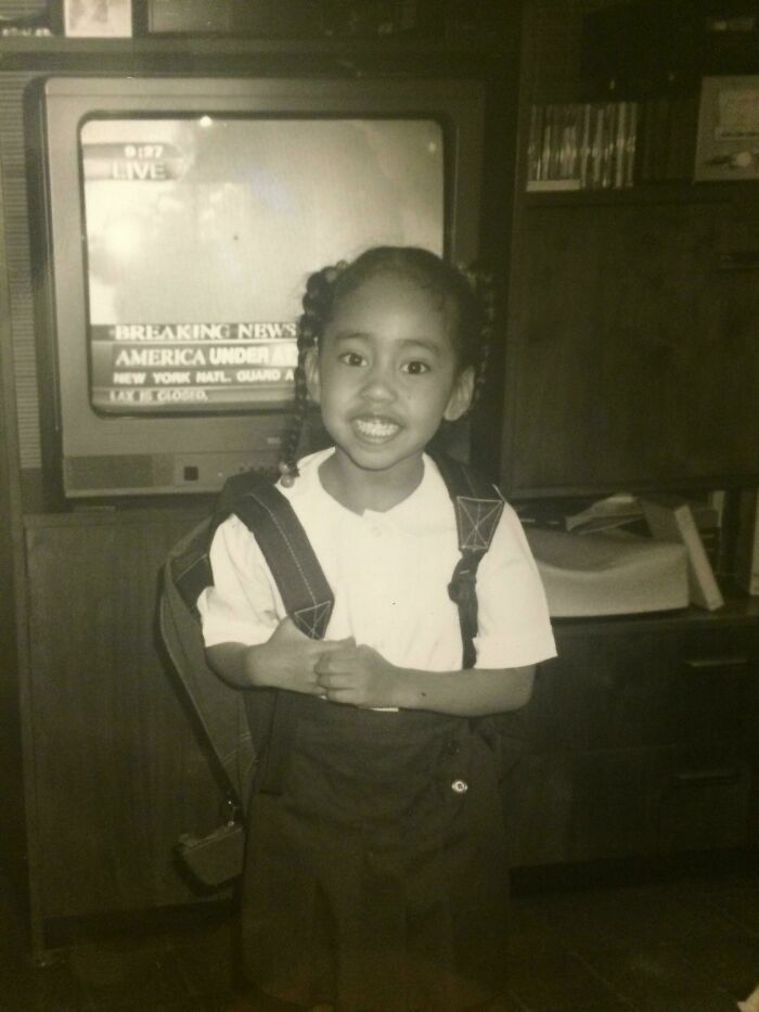 Niña posando sonriente en el colegio mientras al fondo la television transmite noticias impactantes en fotos divertidas.