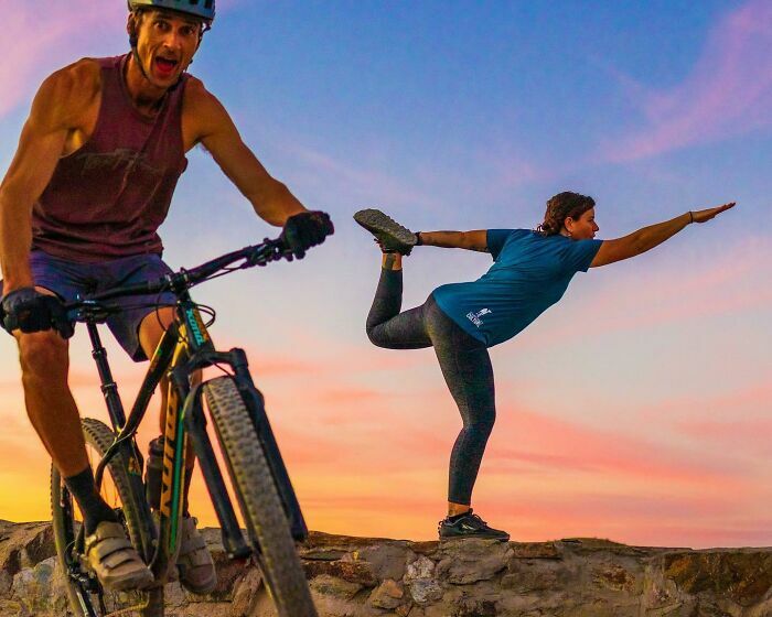 Hombre en bicicleta en primer plano con mujer haciendo yoga al fondo, fotos divertidas