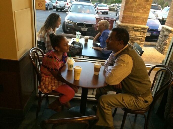 Padre e hija en una cafetería con una pareja al fondo en fotos divertidas