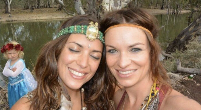 Dos mujeres sonrientes con niña molesta en el fondo mostrando un fondo cómico