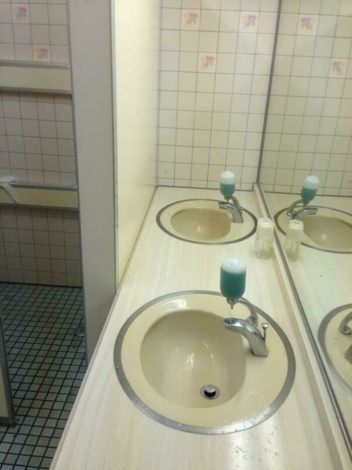 Lavabo mal instalado con dispensador de jabón bloqueando el agua, uno de los fallos de diseño.