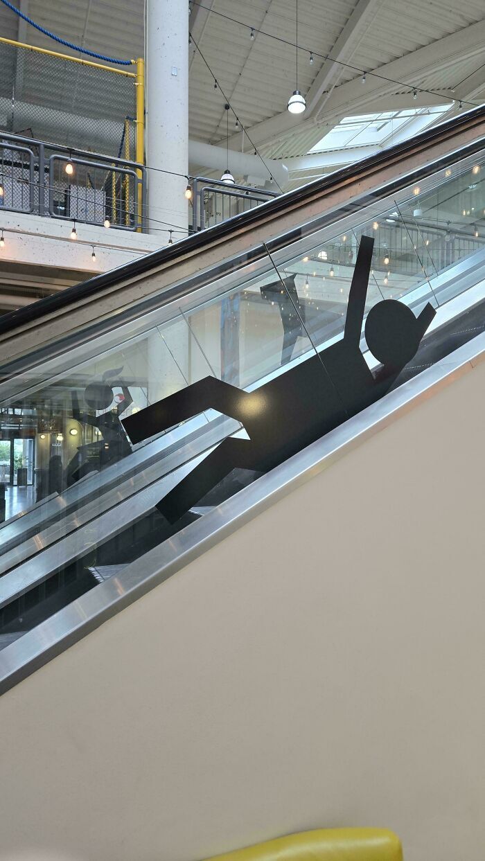 Adhesivo de silueta cayéndose en el cristal de una escalera mecánica, ejemplo de fallos de diseño.