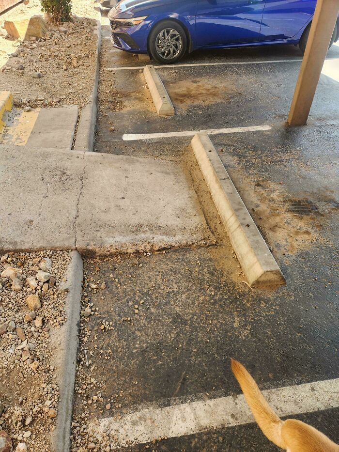 Rampa para discapacitados bloqueada por un bordillo de concreto en un estacionamiento, ejemplo de fallos de diseño.