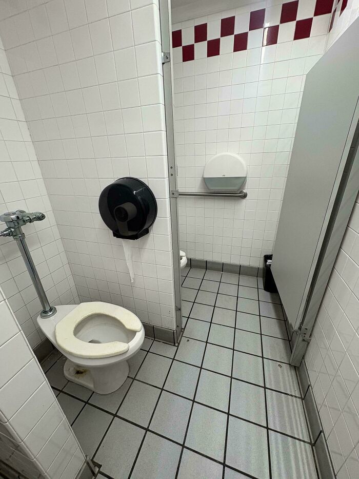 Bano publico con el dispensador de papel lejos del inodoro, evidente entre diversos fallos de diseno.