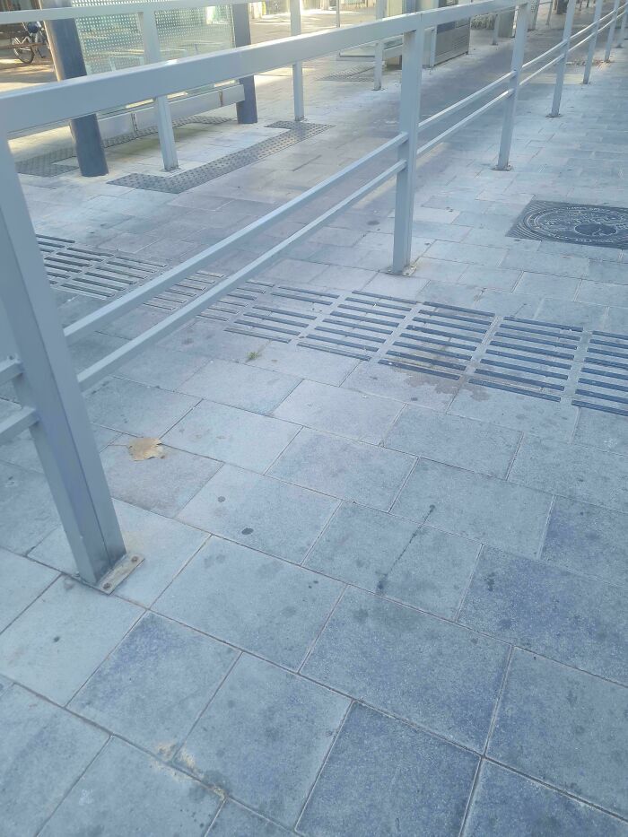 Barandilla de metal instalada sobre la guia podotactil del suelo, uno de los peores fallos de diseno.