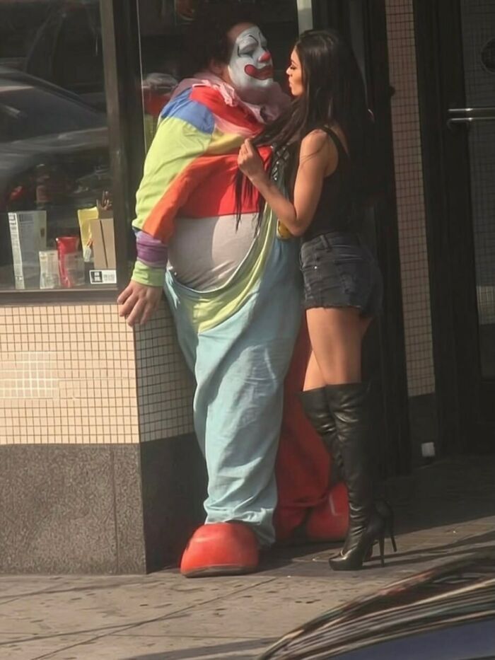 Una mujer coqueteando con un hombre disfrazado de payaso en la calle, uno de tantos memes sin contexto.