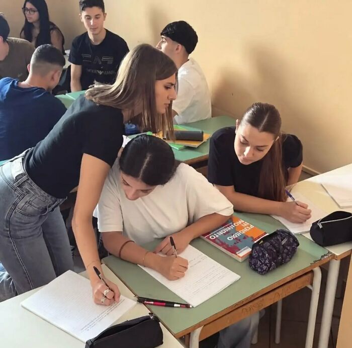 Imágenes y memes sin contexto de una estudiante ayudando a otra escribiendo en su cuaderno durante la clase