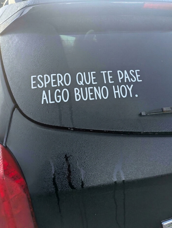 Coche oscuro con un vinilo y divertidas pegatinas en los parachoques de los coches con mensaje positivo.