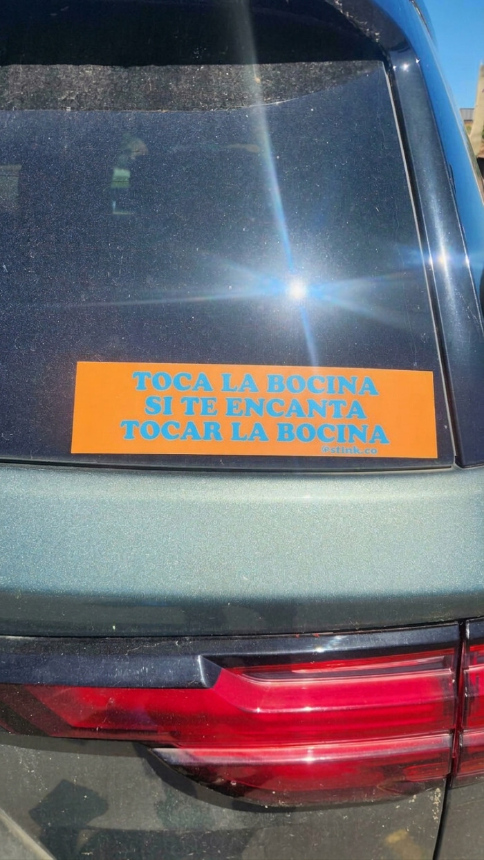 Coche con pegatinas en los parachoques de color naranja con el texto Toca la bocina si te encanta tocar la bocina.