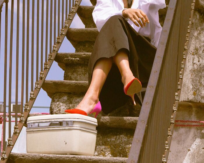 Una mujer sentada en unas escaleras con maletas tras enterarse de trabajadores despedidos de su empleo.
