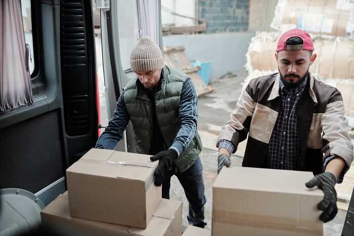 Dos trabajadores descargando cajas de una furgoneta antes de ser despedidos.