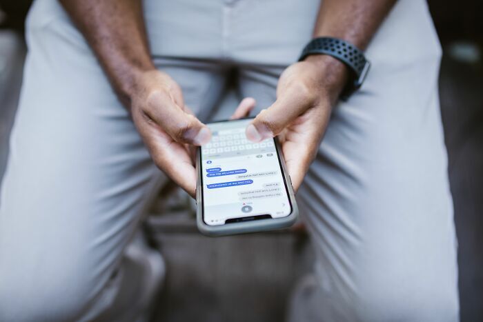 Manos de una persona escribiendo en un teléfono celular sobre historias de trabajadores despedidos.