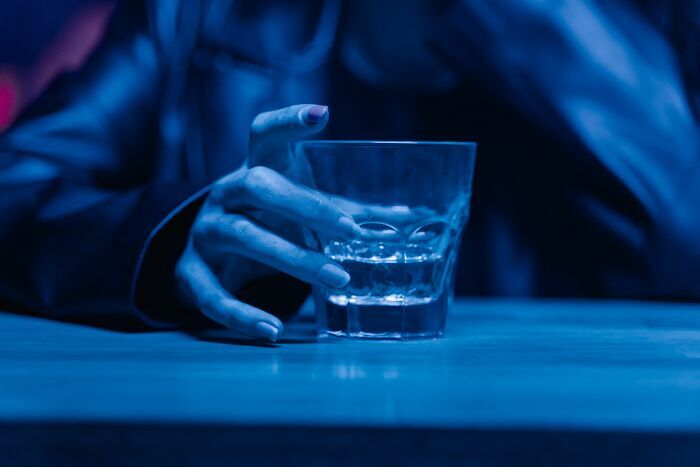 Mano sosteniendo un vaso con bebida en un bar, historia de trabajadores que fueron despedidos casi inmediatamente.
