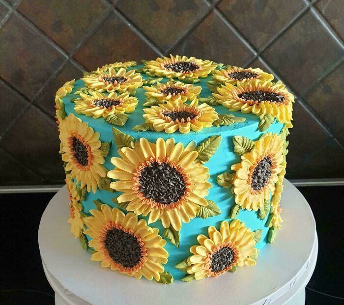 Pastel azul turquesa decorado con girasoles amarillos en relieve, arte de la repostería.
