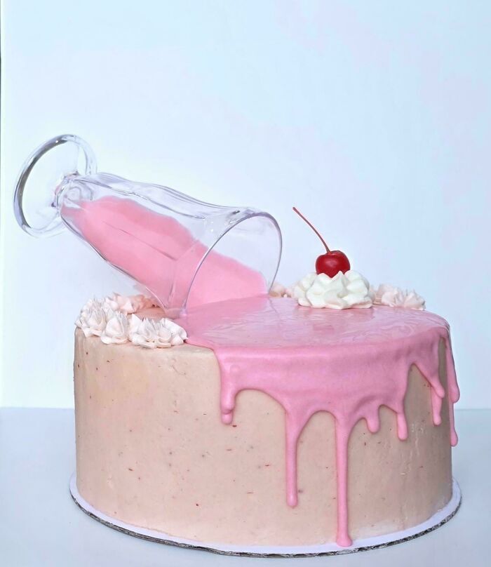 Pastel creativo decorado con un vaso derramando glacé rosa, obra de alta repostería.