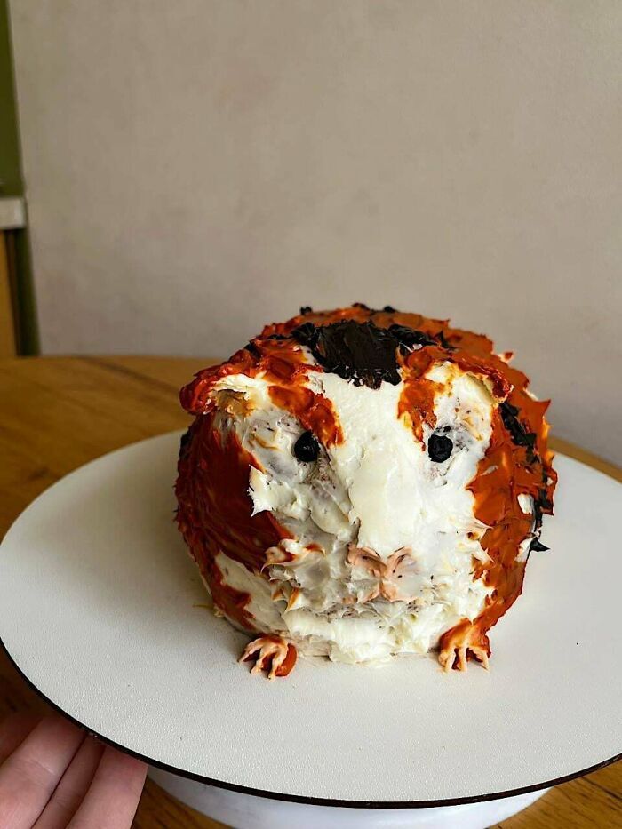 Pastel decorado con crema blanca y marrón en forma de cobaya, diseño original de repostería.