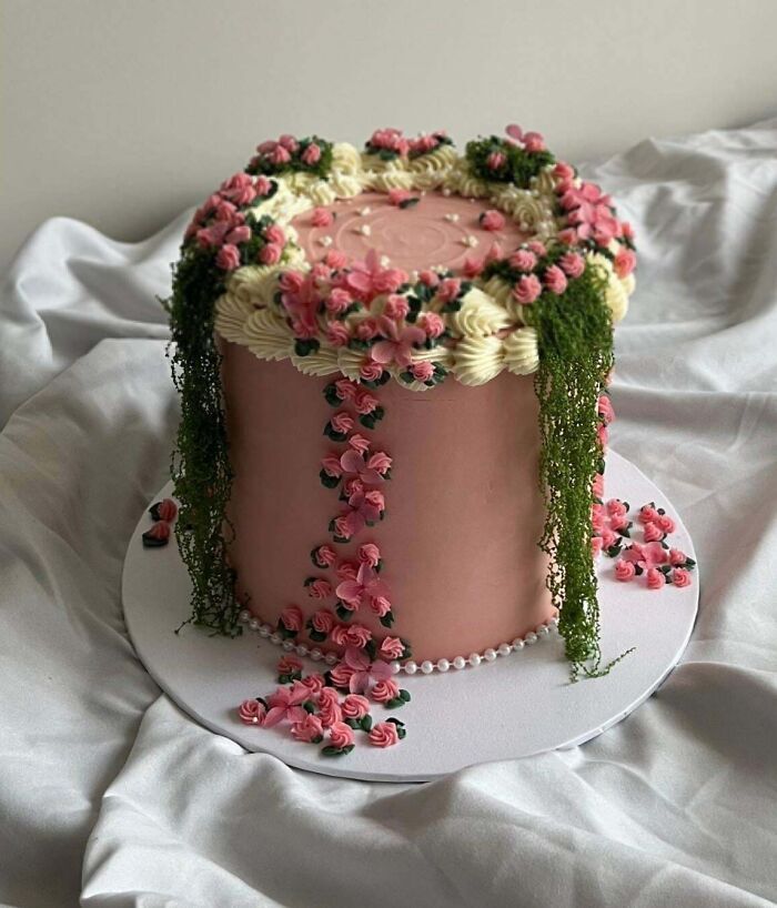 Pastel rosa decorado con hermosas flores de crema en alta repostería.